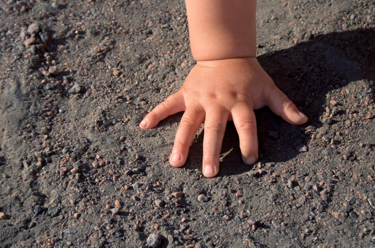 Small hand of a child touching dark soil