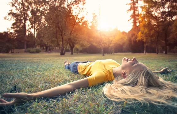 Girl outstretched on the grass while the sun sets